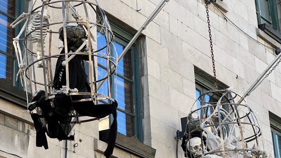 Street in Montreal, QC showing skeletons in big hanging baskets