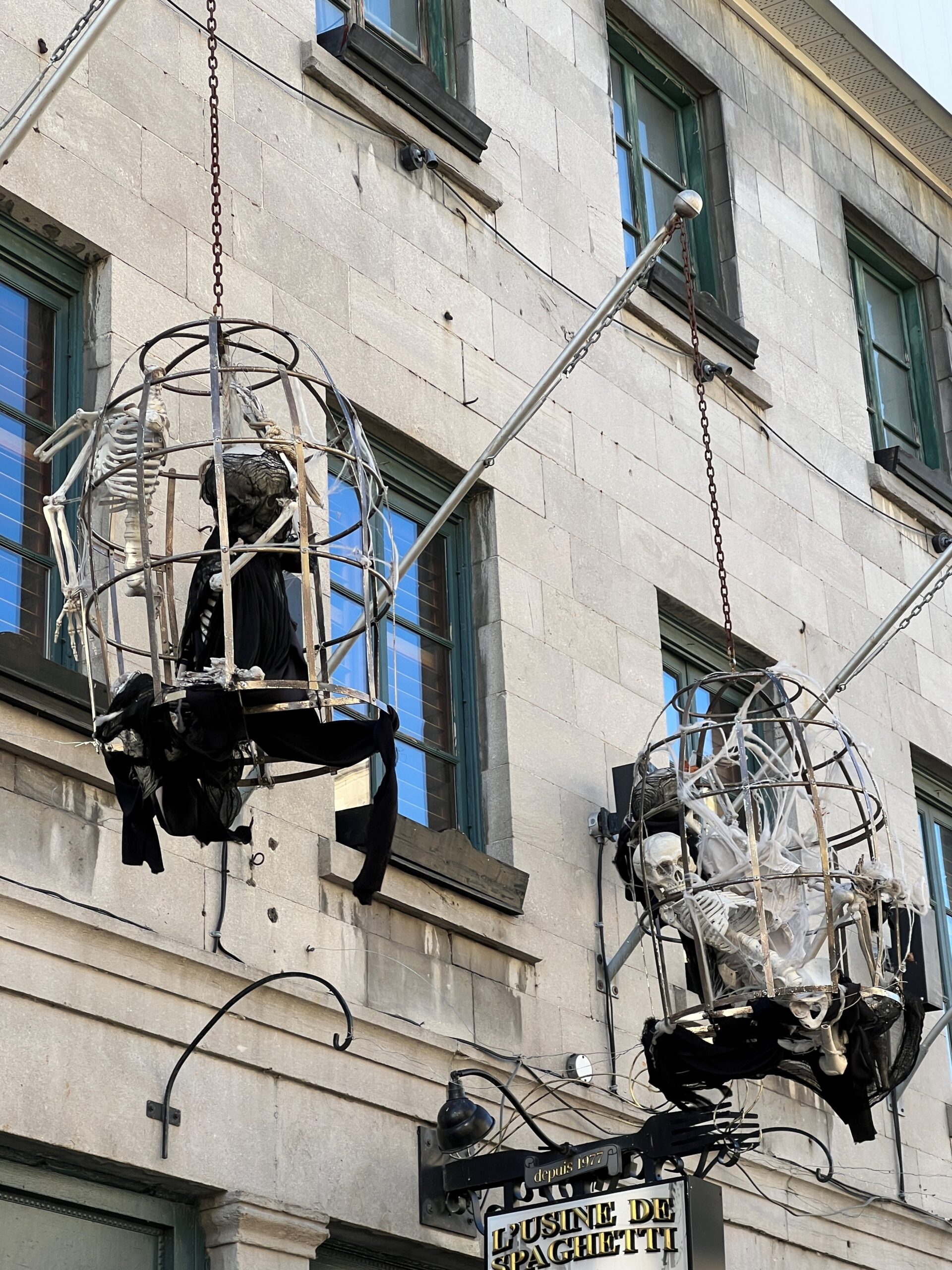 Street in Montreal, QC showing skeletons in big hanging baskets